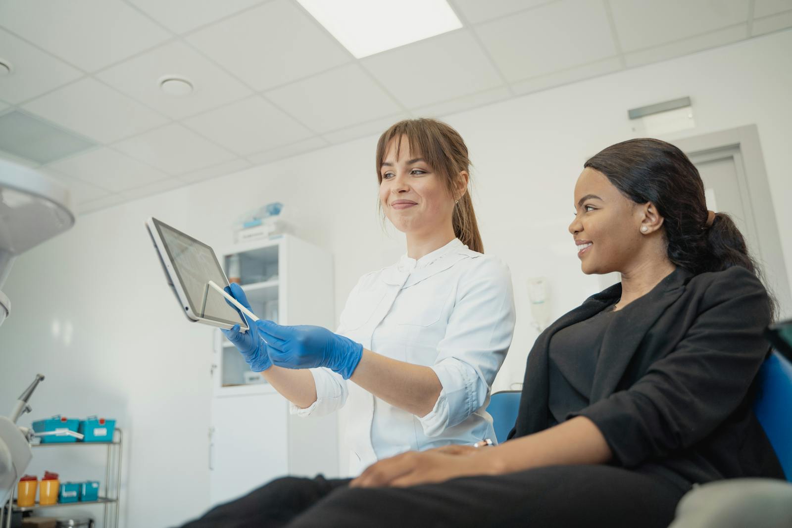 Dentist and patient discussing treatment plan using a tablet in a modern clinic setting, health, preventive care